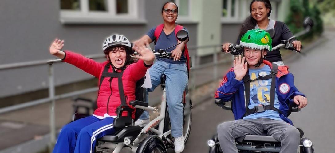 Foto von zwei Teilnehmenden der Ferienbetreuung, die mit zwei Mitarbeitenden mit dem Rollfiets unterwegs sind