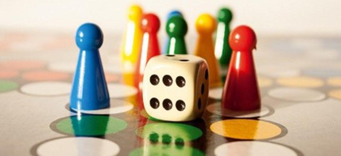 Zu sehen sind bunte Spielsteine auf einem Mensch-ärgere-dich-nicht Brettspiel